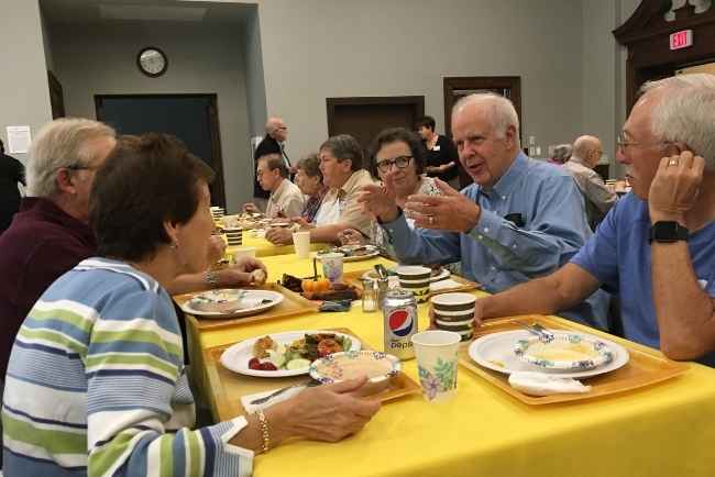 Men and women sitting at a table eating and talking