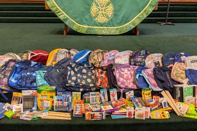 Backpacks and school supplies being blessed during worship