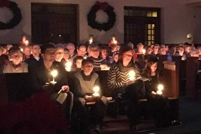 People attending church holding lit candles